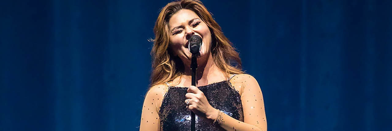 Shania Twain performs onstage in a blue sparkly dress