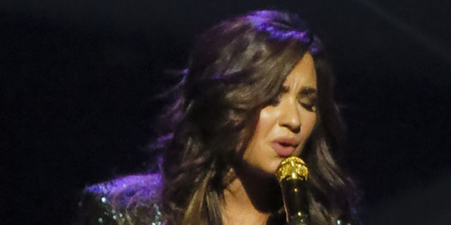 Demi Lovato singing onstage while wearing a black outfit