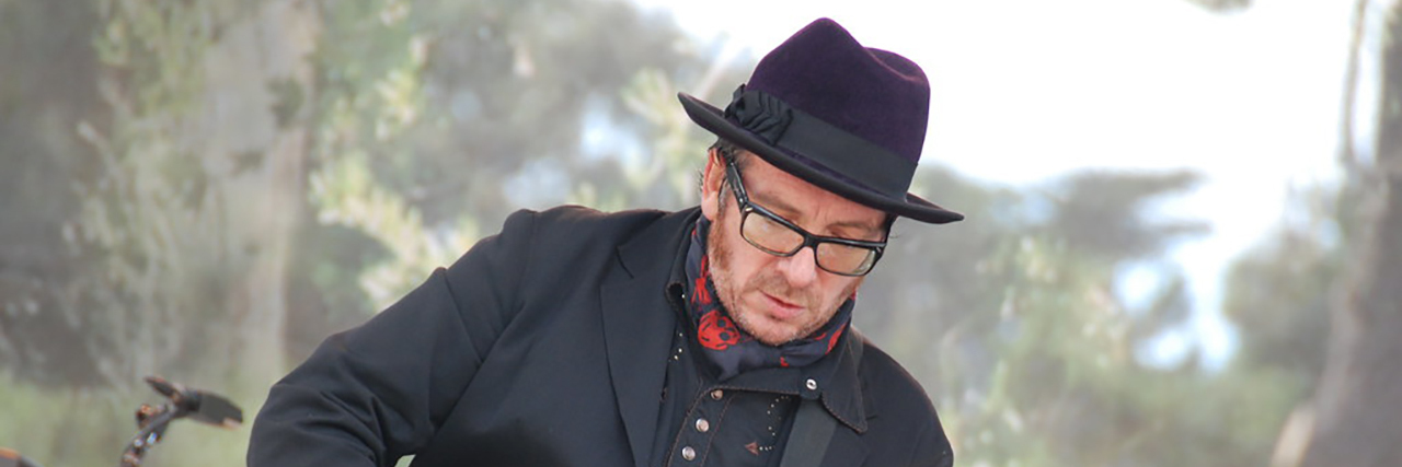 Elvis Costello Cancels European Tour to Recover From Cancer Surgery Elvis Costello playing the guitar at a concert