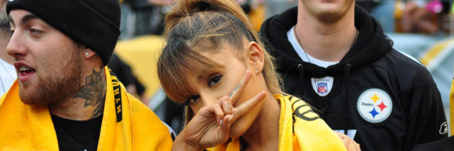 Ariana Grande throws a piece sign while at a sports game