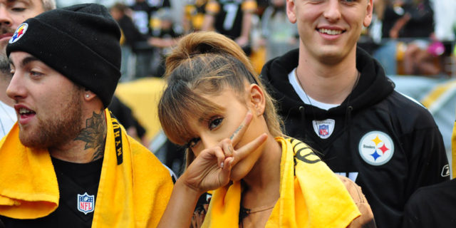 Ariana Grande throws a piece sign while at a sports game