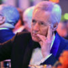 Alex Trebek looks onstage while sitting at a gala