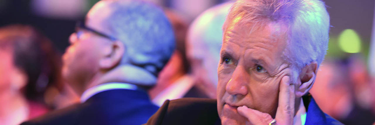 Alex Trebek Shares He's in 'Near Remission' From Pancreatic Cancer Alex Trebek looks onstage while sitting at a gala