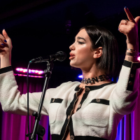 Dua Lupia points at the crowd while singing onstage.