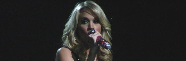 Carrie Underwood performs onstage in a black outfit.