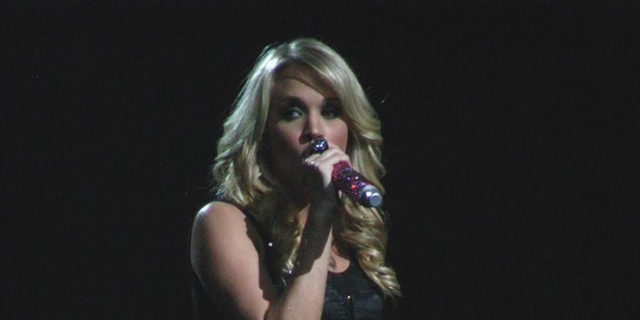 Carrie Underwood performs onstage in a black outfit.