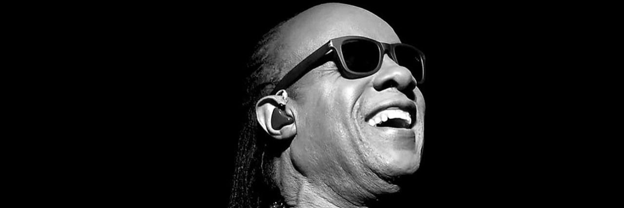 Steve Wonder poses onstage while wearing a black outfit