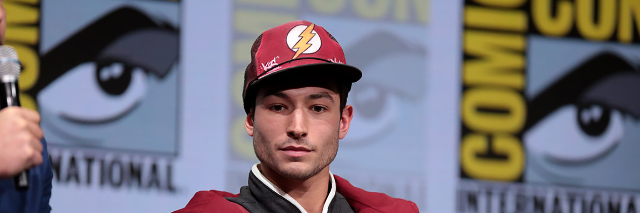 Ezra Miller looks down while wearing a Flash costume at Comic Con