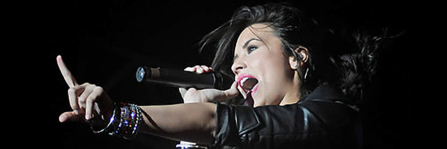Demi Lovato singing onstage while wearing a black outfit