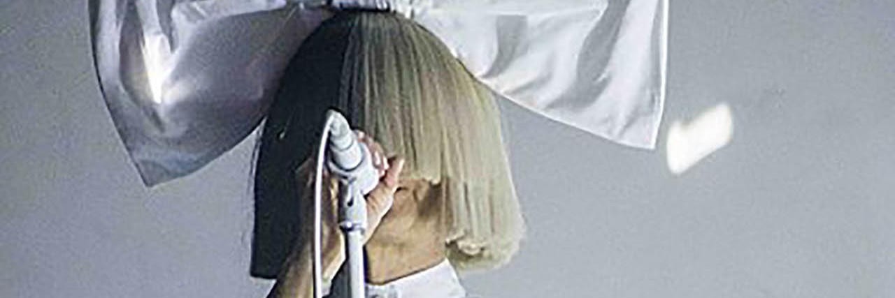 Sia Opens Up About a Near Suicide Attempt in Rolling Stone Interview Sia singing onstage with a giant bow on her head