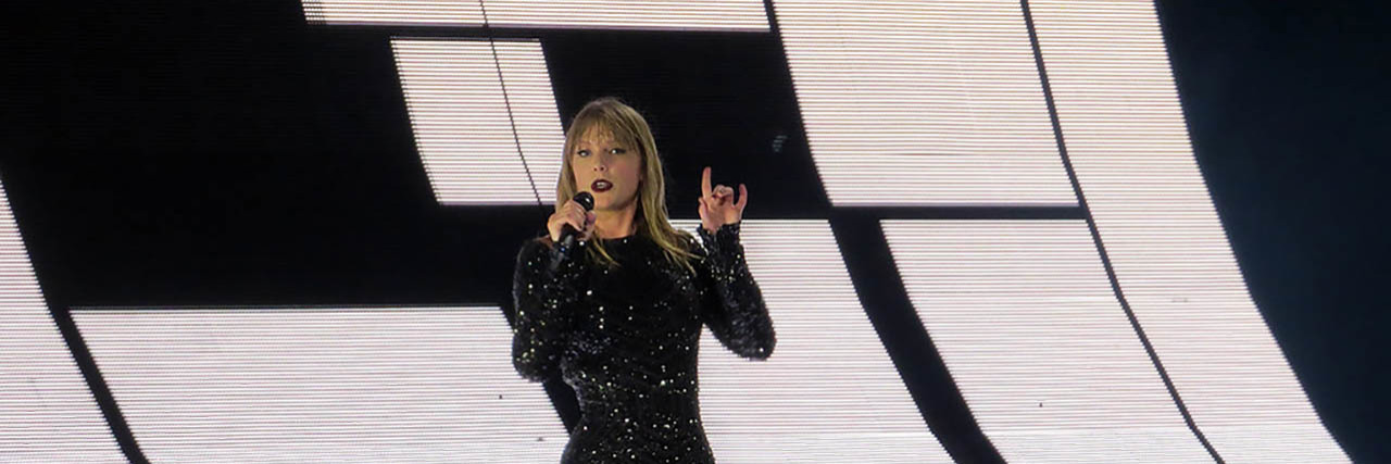 Taylor Swift performs onstage while wearing a black ensemble