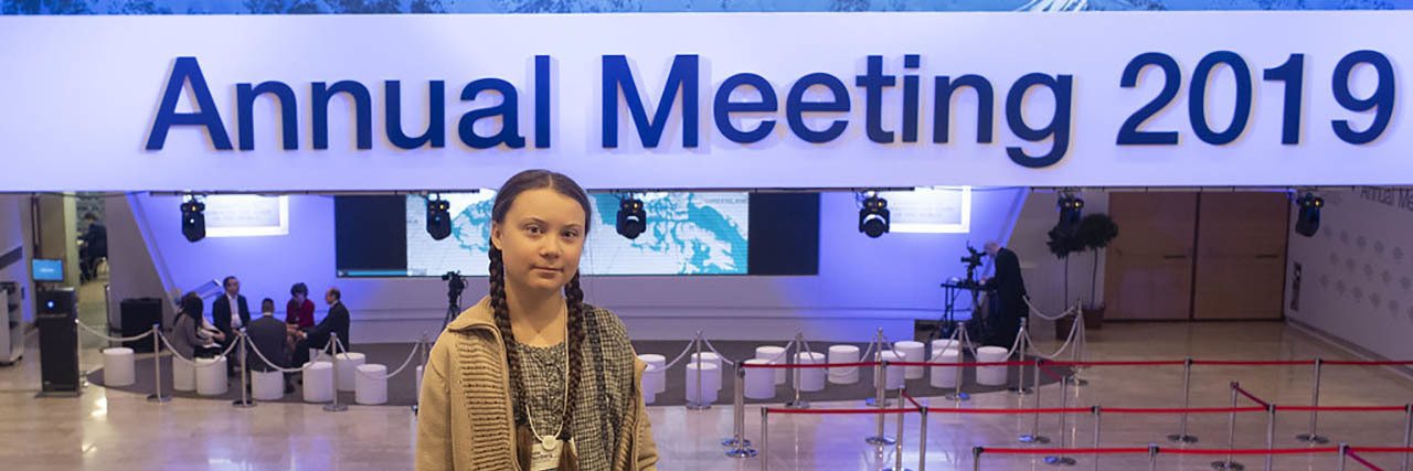 Greta Thunberg poses in front of a sign at a summit