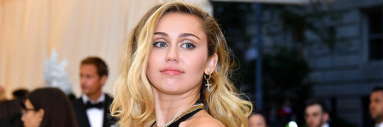 Miley Cyrus poses in a black dress while on the red carpet