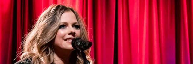 Avril Lavigne sings with her guitar at a Grammy Museum event
