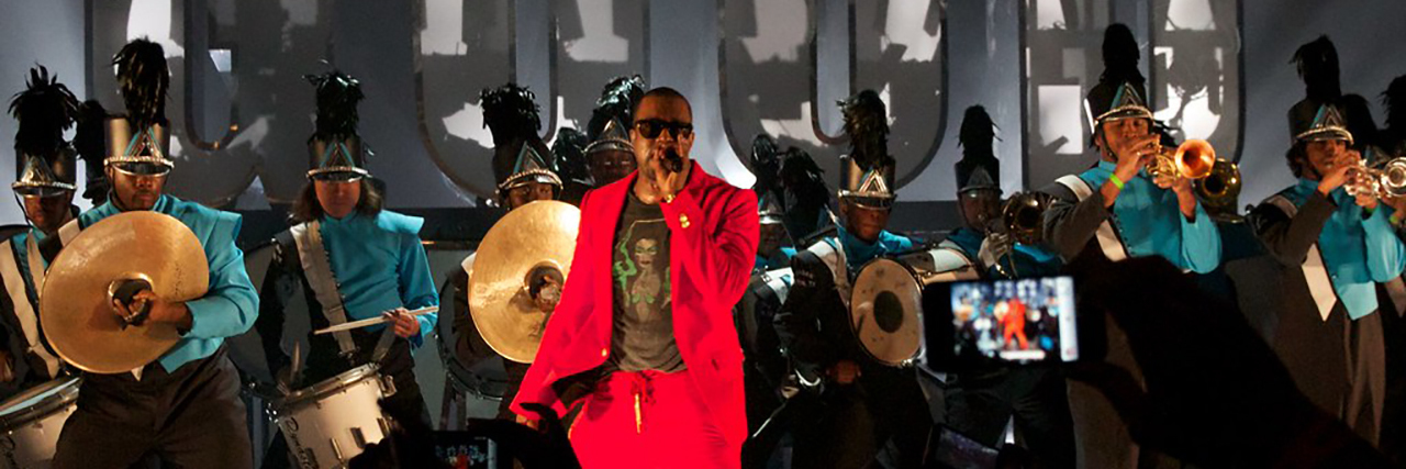 Kanye West performs in a red suit