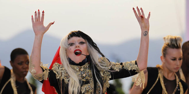 Lady Gaga Shares Open Letter About Her Experience With Mental Illness and PTSD Lady Gaga performs while wearing a gold, back and red ensemble