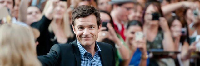 Jason Bateman smiles while getting out of his car