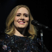 Adele performs onstage while wearing a black gown