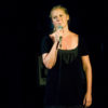 Amy Schumer in a black dress talking onstage