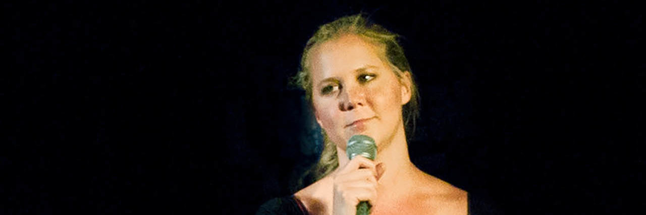 Amy Schumer in a black dress talking onstage