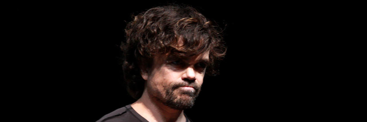 Peter Dinklage crosses his hands over his heart while on stage