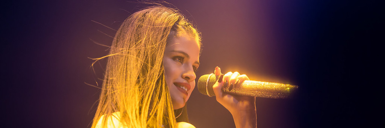 Selena Gomez Wears Fall Risk Bracelet in 'Bad Liar' Music Video Selena Gomez singing onstage while wearing a white costume