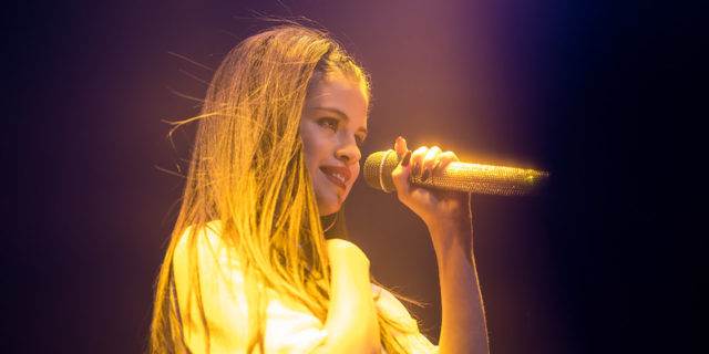 Julia Michaels and Selena Gomez Collaborate on New Single Called 'Anxiety' Selena Gomez singing onstage while wearing a white costume