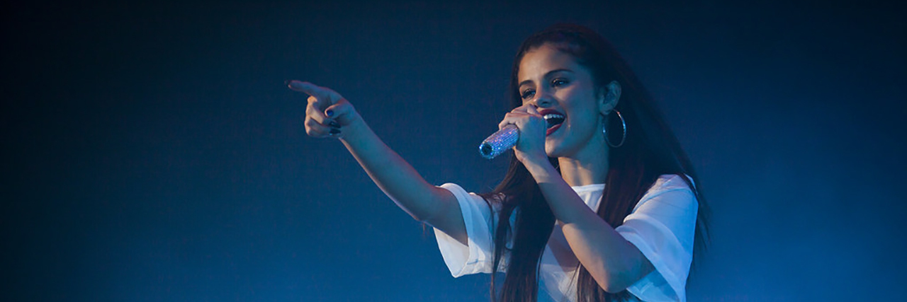 Selena Gomez and Netflix Address '13 Reasons Why' Controversy Selena Gomez singing onstage while wearing a white costume