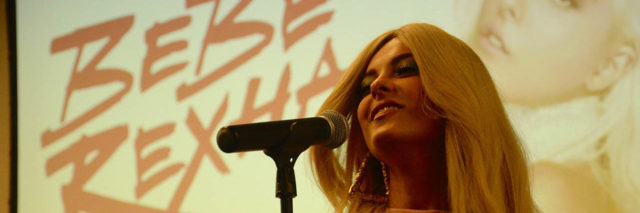 A close-up of Bebe Rexha singing in front of her name