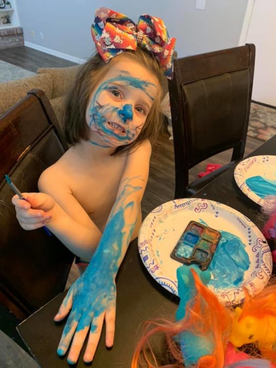 Little girl with paint all over face and body