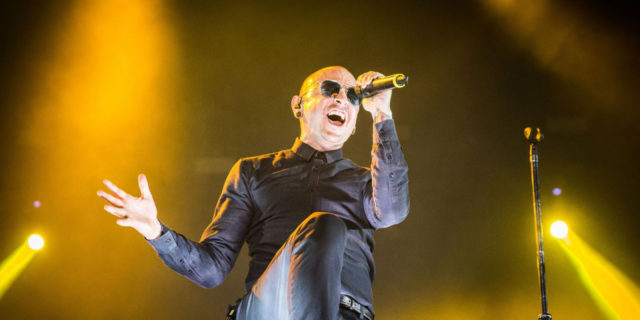 Chester Bennington sings onstage in a black outfit