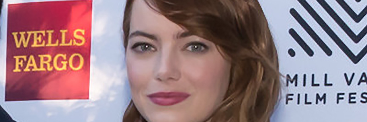 Emma Stone in a black and white dress poses on the red carpet
