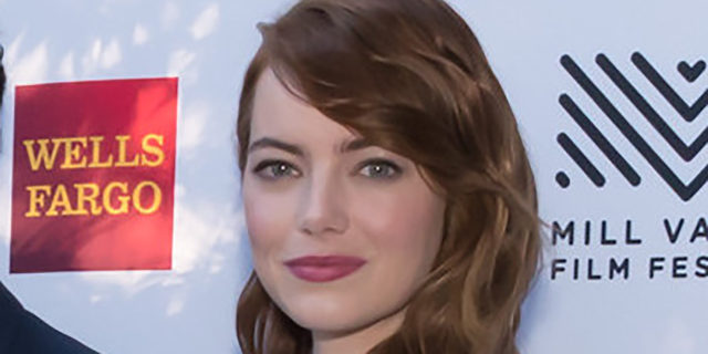 Emma Stone in a black and white dress poses on the red carpet