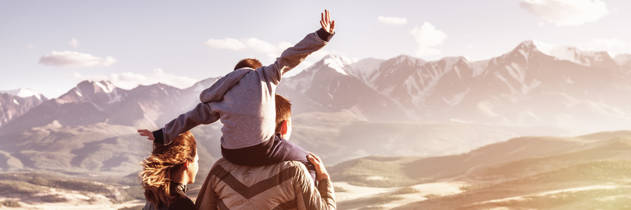 Happy family with son looking at mountains at sunset.