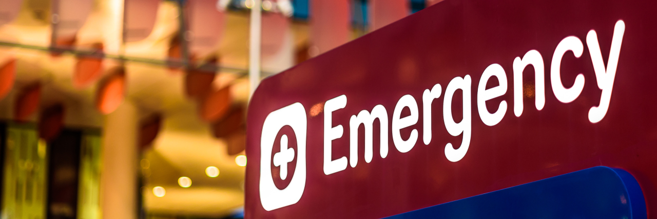 An "Emergency" sign in front of a hospital in the early evening.
