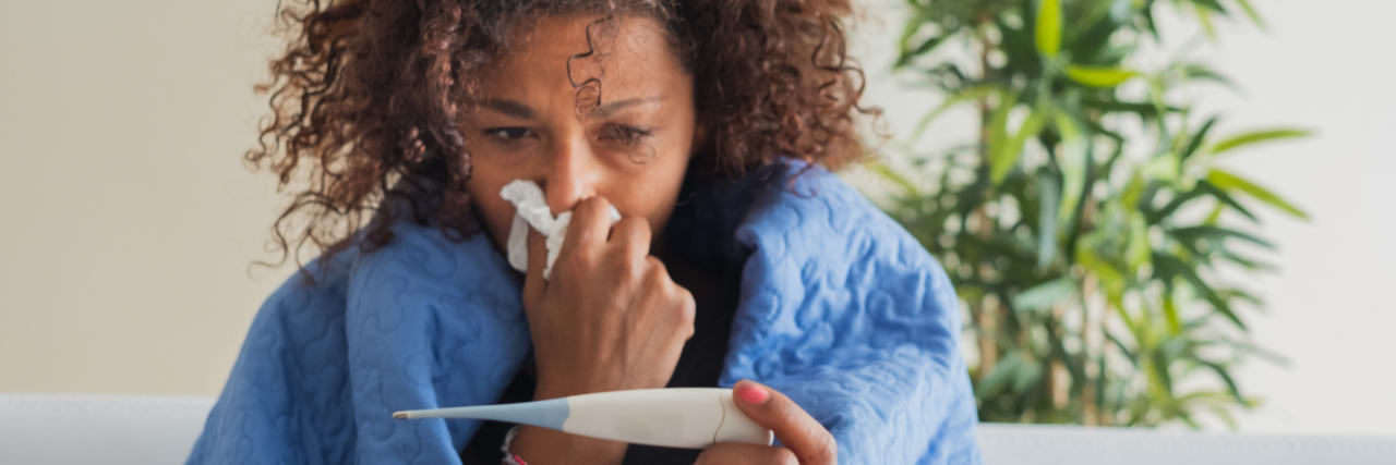 Tips on How to Accurately Check Your Temperature for COVID-19 Woman blowing nose and checking body temperature.