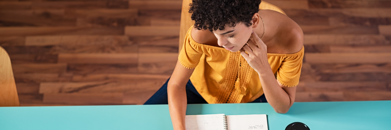 Creating a Schedule in COVID-19 Self-Isolation With Mental Illness woman sitting at a table with journals spread out writing