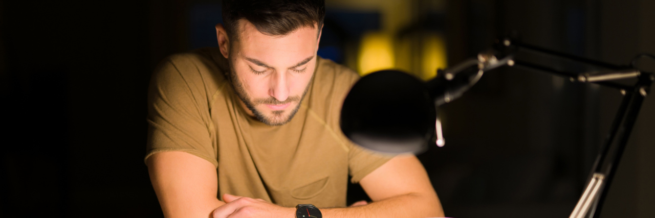 What 'Educational Burnout' Is and How to Prevent It From Happening young man sitting at a desk reading a book, studying