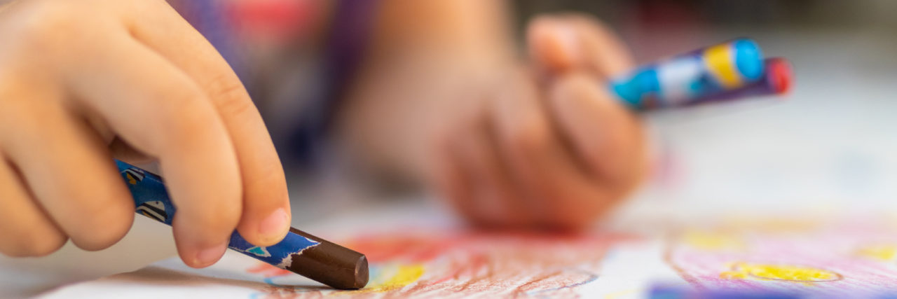 Child coloring with crayons.