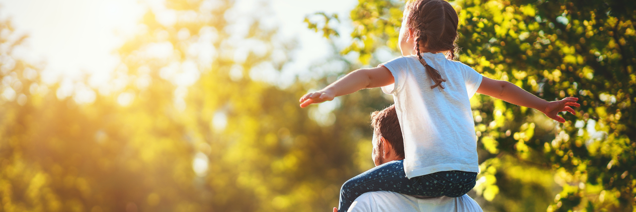 5 Ways to Nurture Your Child's Developing Mental Health a young girl sitting on her dad's shoulders at apark