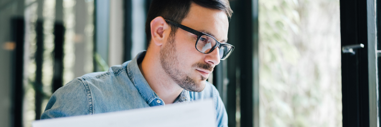 Man with glasses sitting at a computer