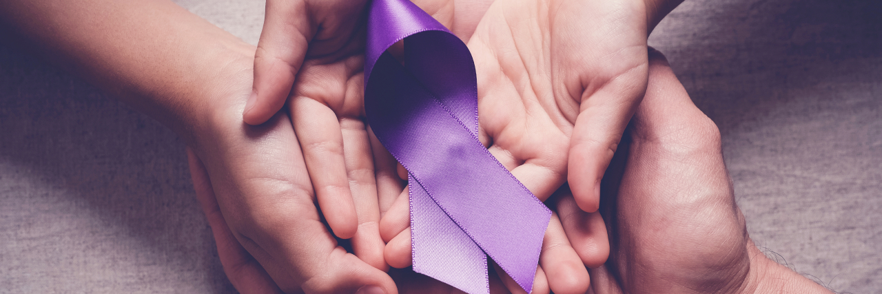Adult and child hands holding purple ribbons