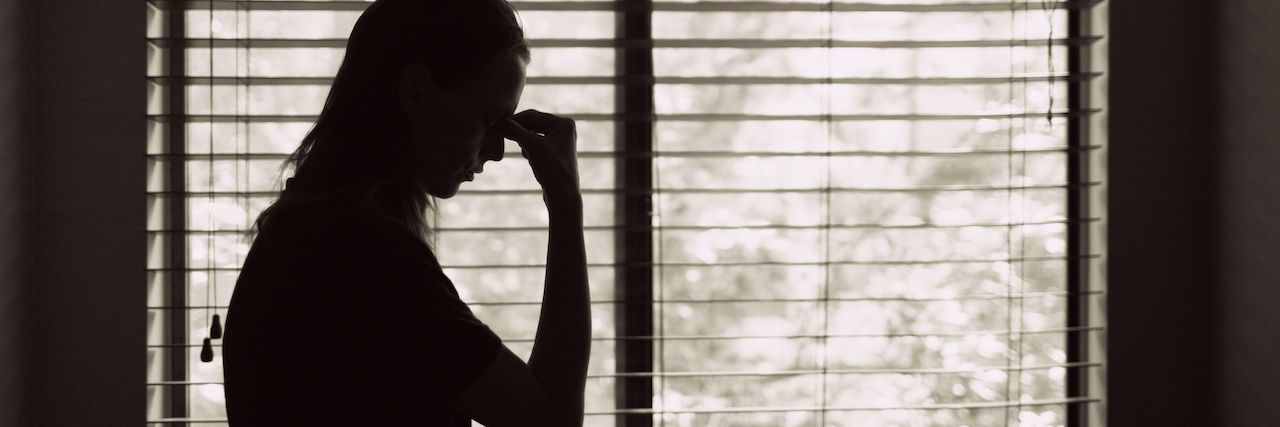 How to Mourn Someone Without a Funeral During COVID-19 A woman indoors in front of a window
