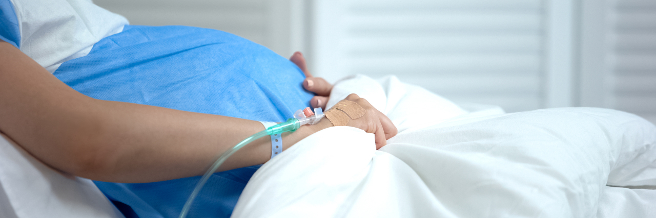 What Doctors Said When I Went Into Early Labor With My Son A pregnant woman in cradling her stomach in a hospital bed.
