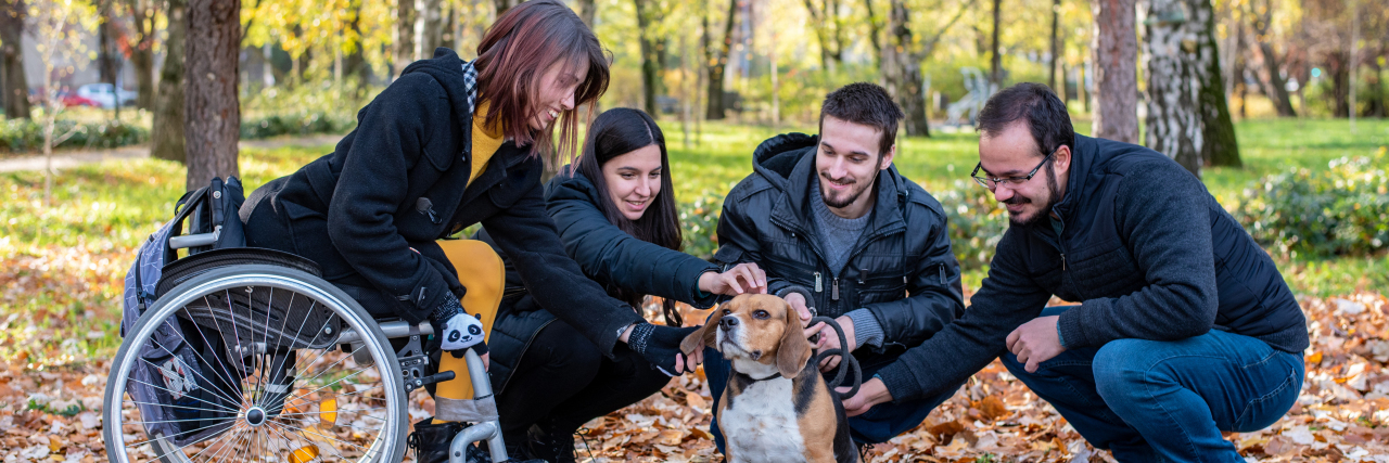Avoid Negative Language Like 'Suffers From' When Discussing Disability Young disabled woman in a wheelchair playing with dog and friends.