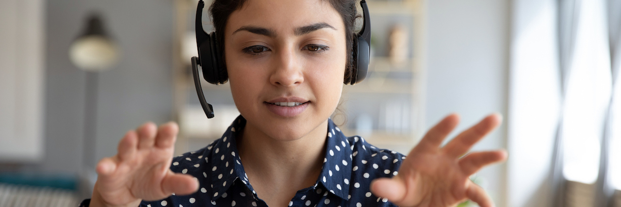 Therapists Create Virtual EMDR Trauma Therapy During COVID-19 Indian young woman wearing a headset in front of a computer gesturing at the screen