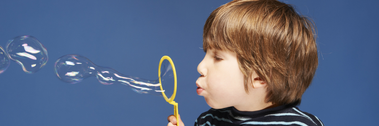 Close up of boy blowing bubbles