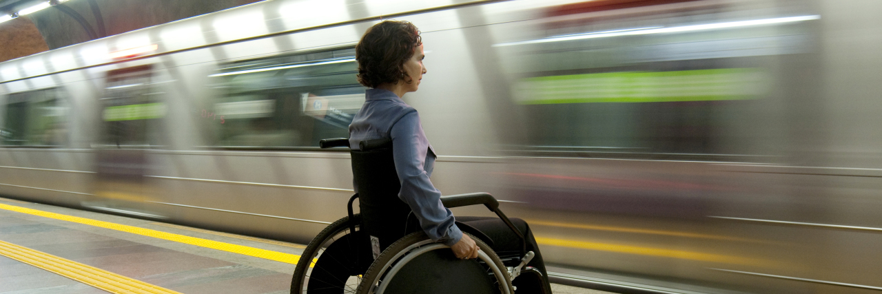 Woman in a wheelchair at a train station.