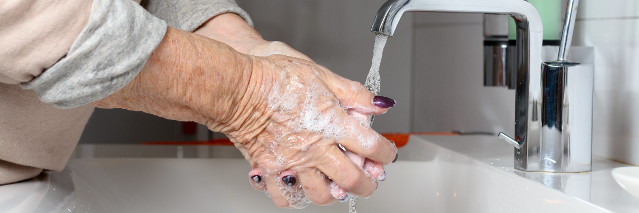 Elderly woman washing hands.
