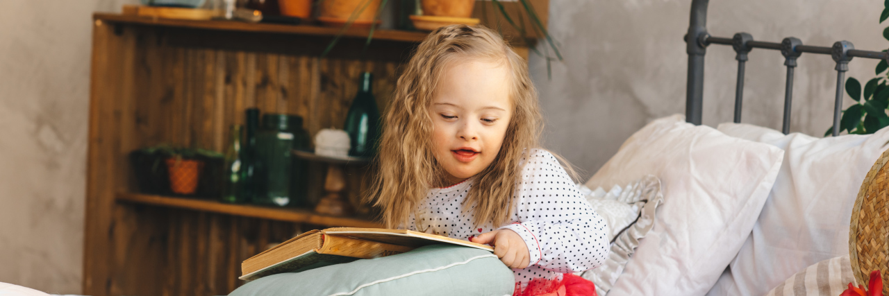 Girl with Down syndrome reading a book.